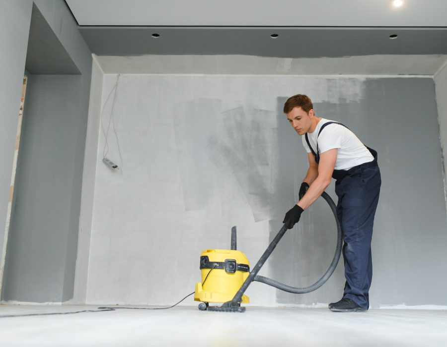 A worker vacuums a room after repairing the floors. Apartment after renovation with a vacuum cleaner