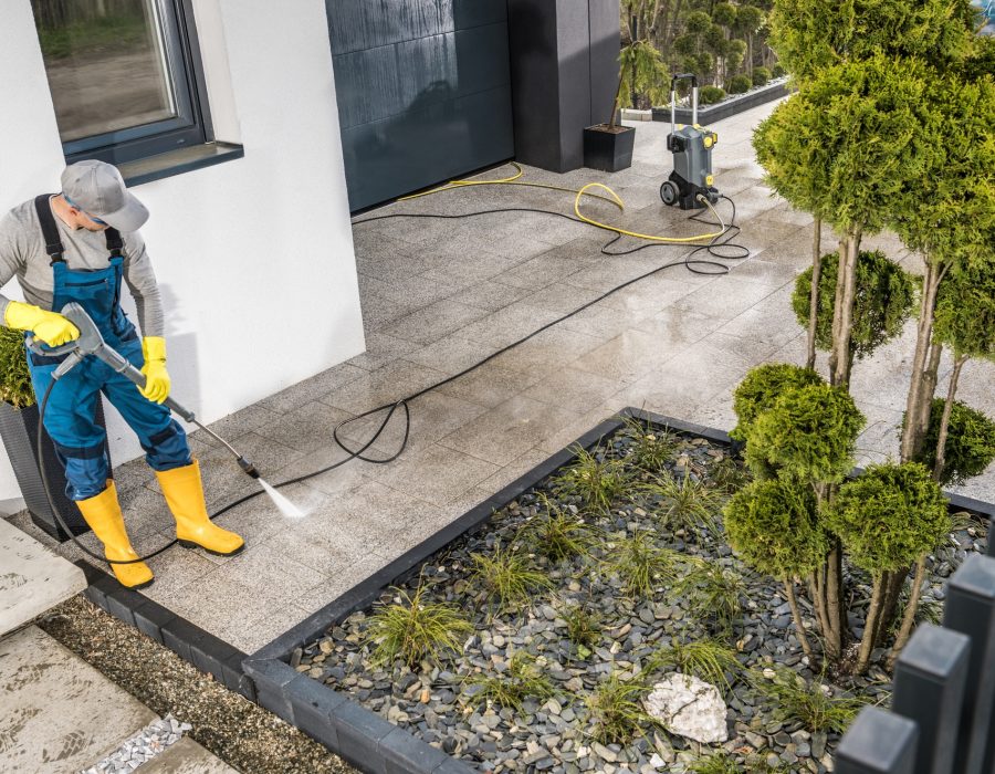 Men Pressure Washing House Surrounding Concrete Elements